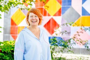 Eine Frau mit rotem Haar steht vor einer lebhaften, mehrfarbigen Wand. &copy; RUB, Marquard