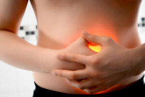 An individual holding their stomach in discomfort, indicating stomach pain. © Roberto Schirdewahn